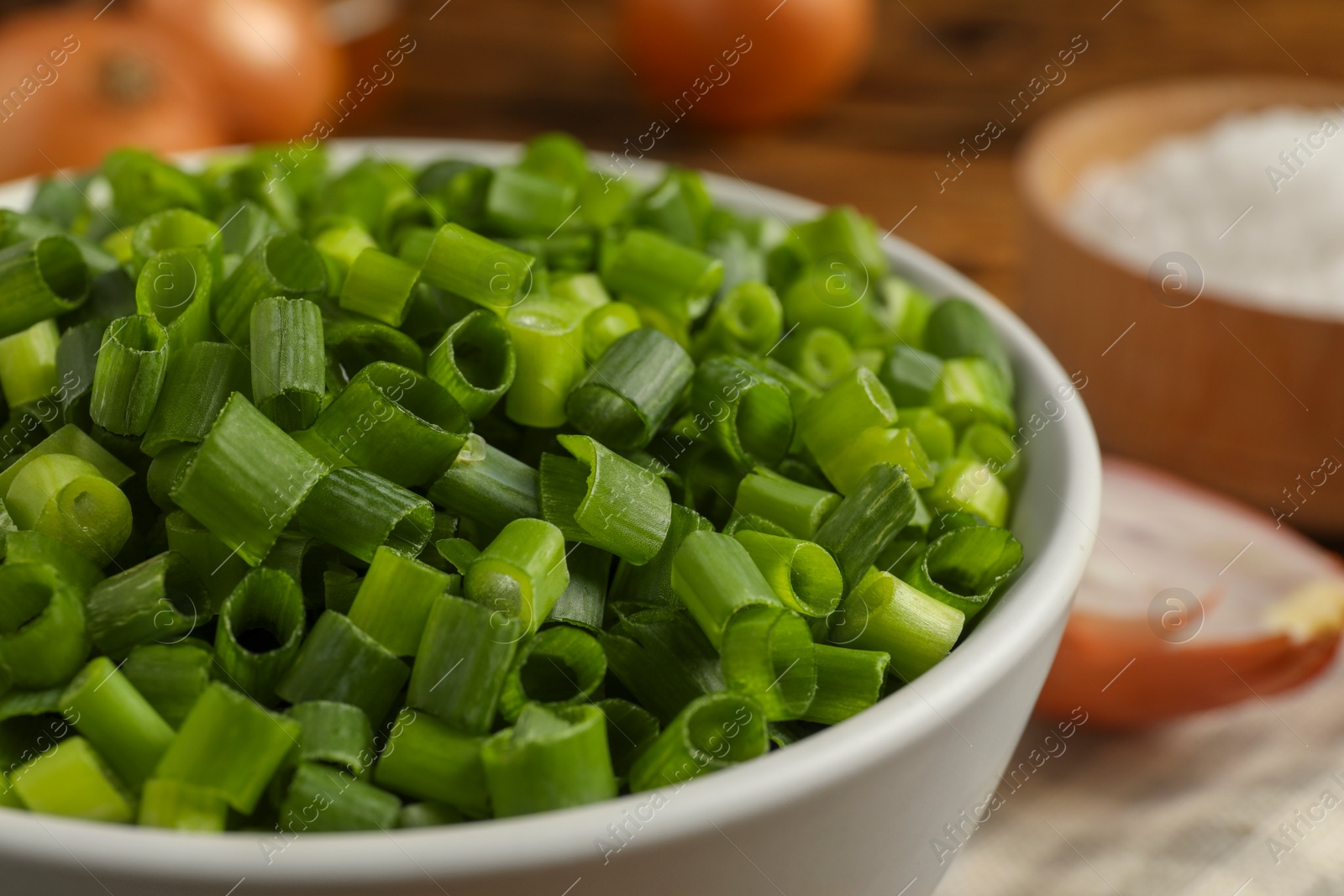 Photo of Chopped fresh green onion in bowl, closeup