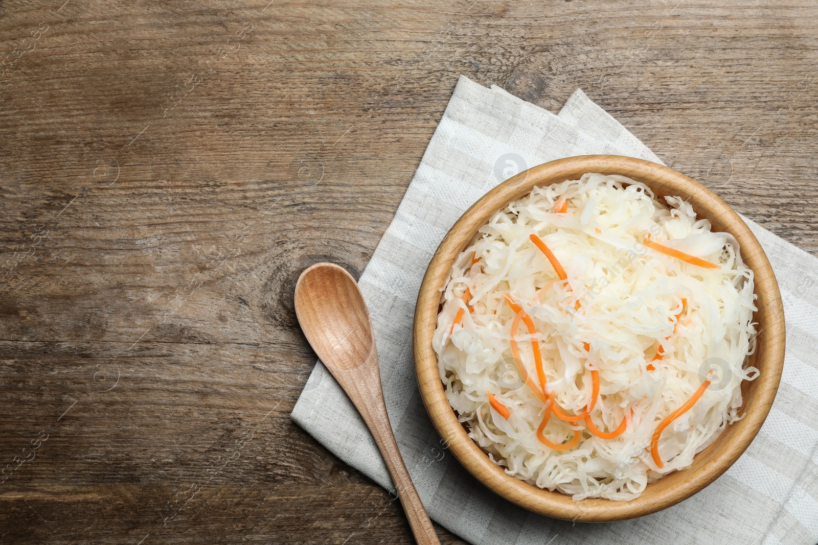 Photo of Tasty fermented cabbage on wooden table, flat lay. Space for text