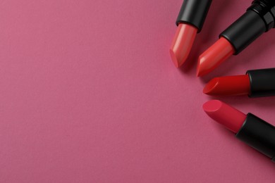 Photo of Beautiful lipsticks on pink background, flat lay. Space for text