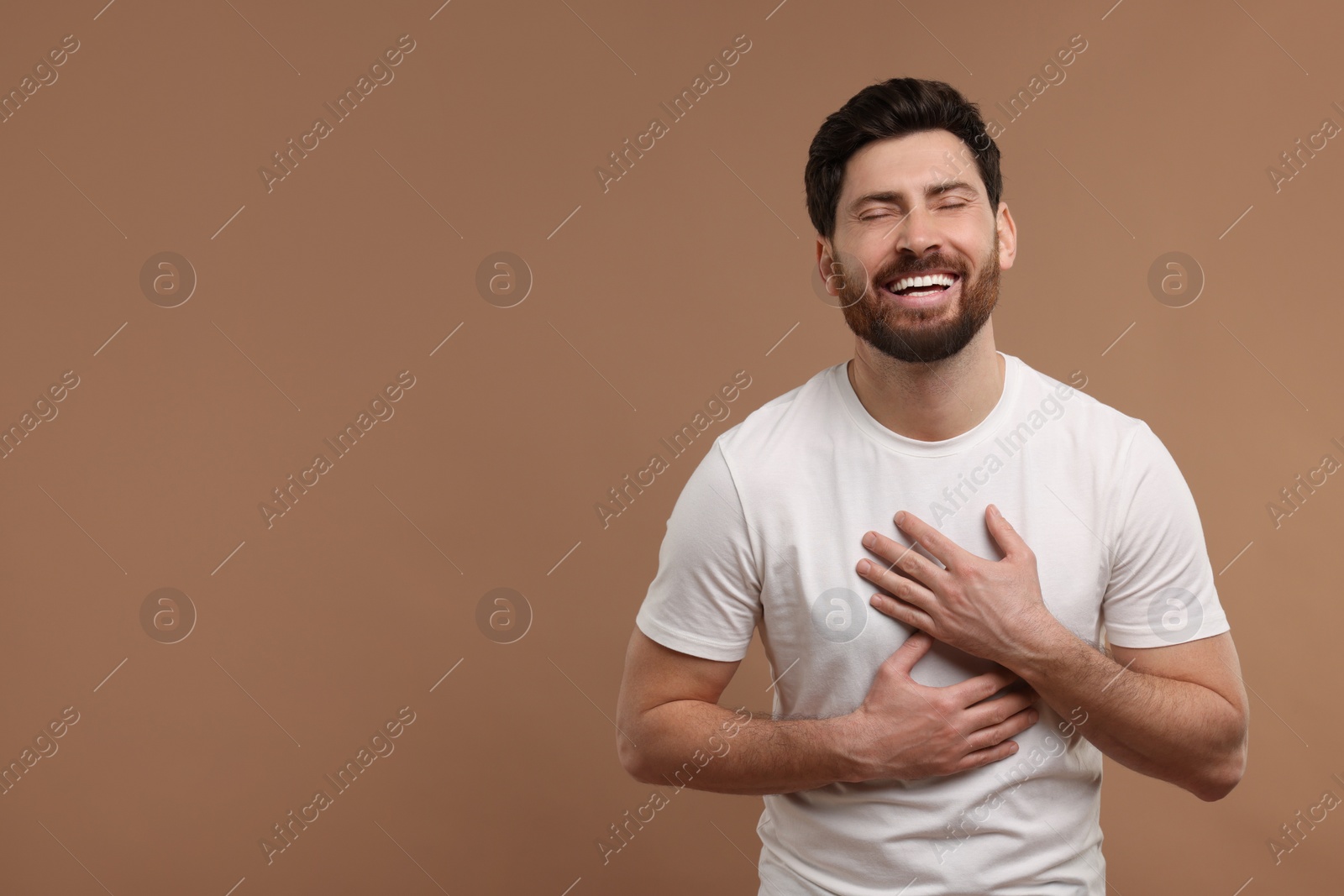 Photo of Handsome man laughing on light brown background. Space for text