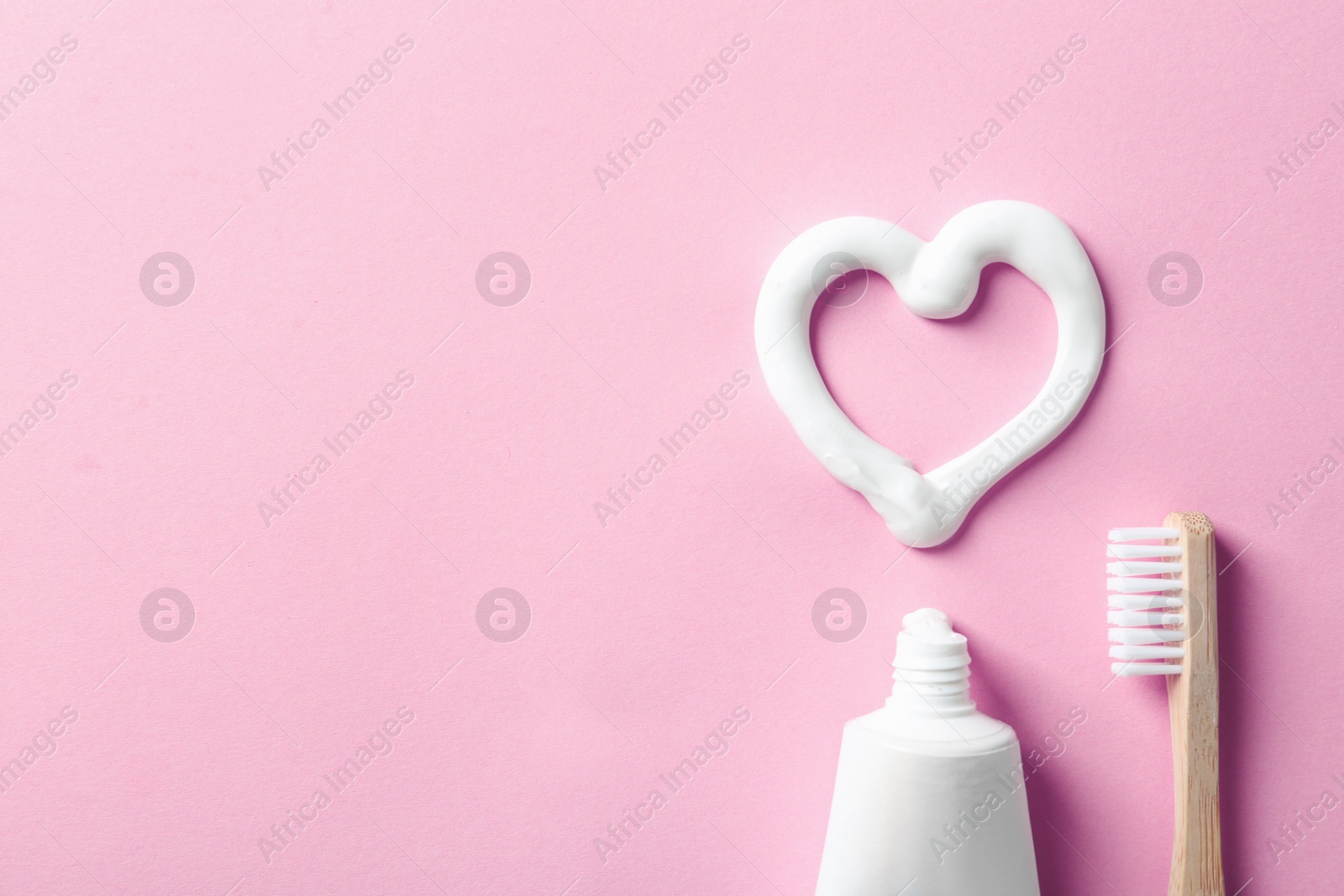 Photo of Flat lay composition with heart shape made of toothpaste and space for text on color background, top view