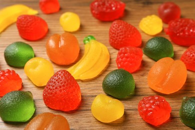 Photo of Delicious gummy fruit shaped candies on wooden table, closeup
