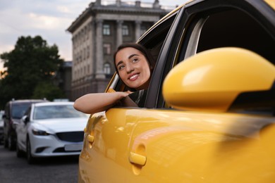 Photo of Beautiful young woman looking out of taxi window outdoors
