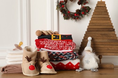 Photo of Baby clothes, accessories and Christmas decor on wooden table