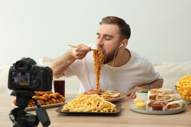 Food blogger recording eating show on camera against light background. Mukbang vlog