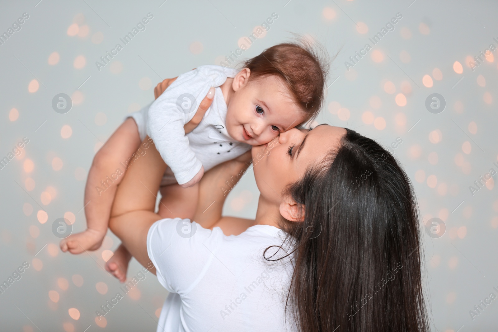 Photo of Young mother with her cute little baby against defocused lights