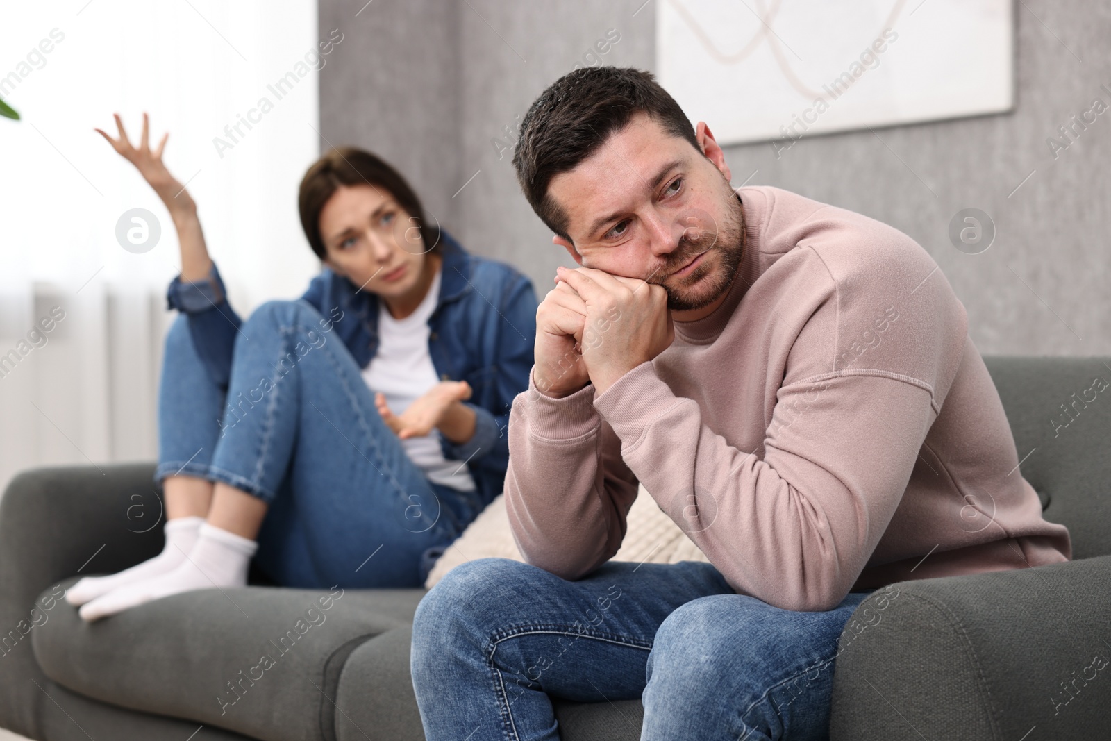 Photo of Offended husband ignoring his wife indoors, selective focus. Relationship problems