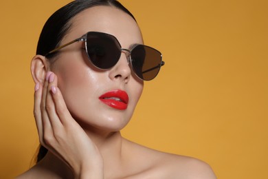 Photo of Attractive woman in fashionable sunglasses against orange background