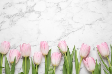 Beautiful tulips  on white marble table, flat lay. Space for text