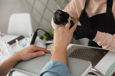 Professional manicurist working with client in beauty salon, closeup