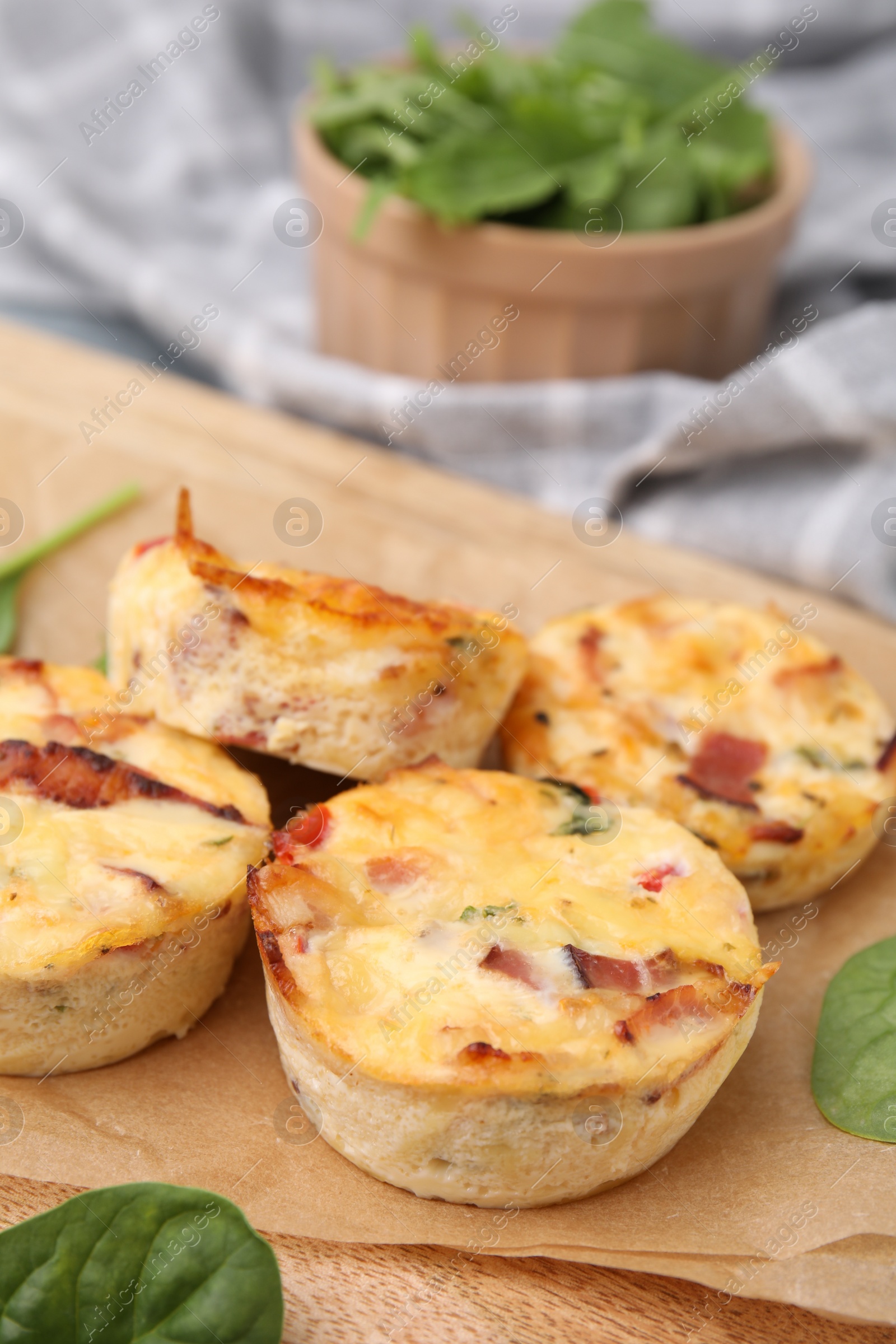 Photo of Delicious egg muffins with cheese and bacon on wooden board, closeup. Space for text