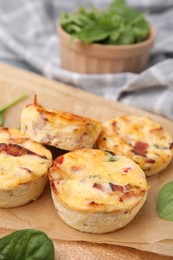 Photo of Delicious egg muffins with cheese and bacon on wooden board, closeup. Space for text