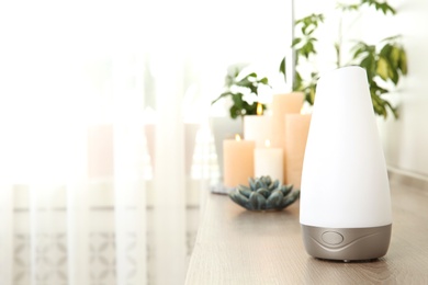 Photo of Composition with modern aroma humidifier on wooden shelf indoors, space for text