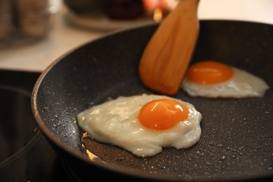 Photo of Frying pan with cooked eggs on stove, closeup