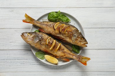 Photo of Tasty homemade roasted perches on white wooden table, top view. River fish