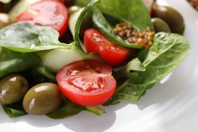 Delicious salad with vegetables and olives on plate, closeup