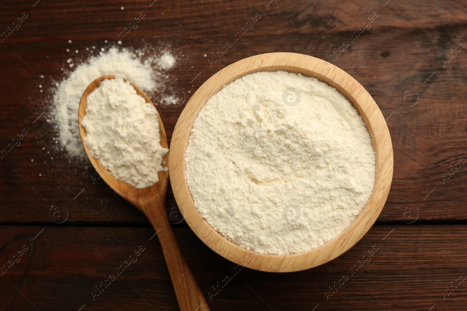 Photo of Baking powder in bowl and spoon on wooden table, top view