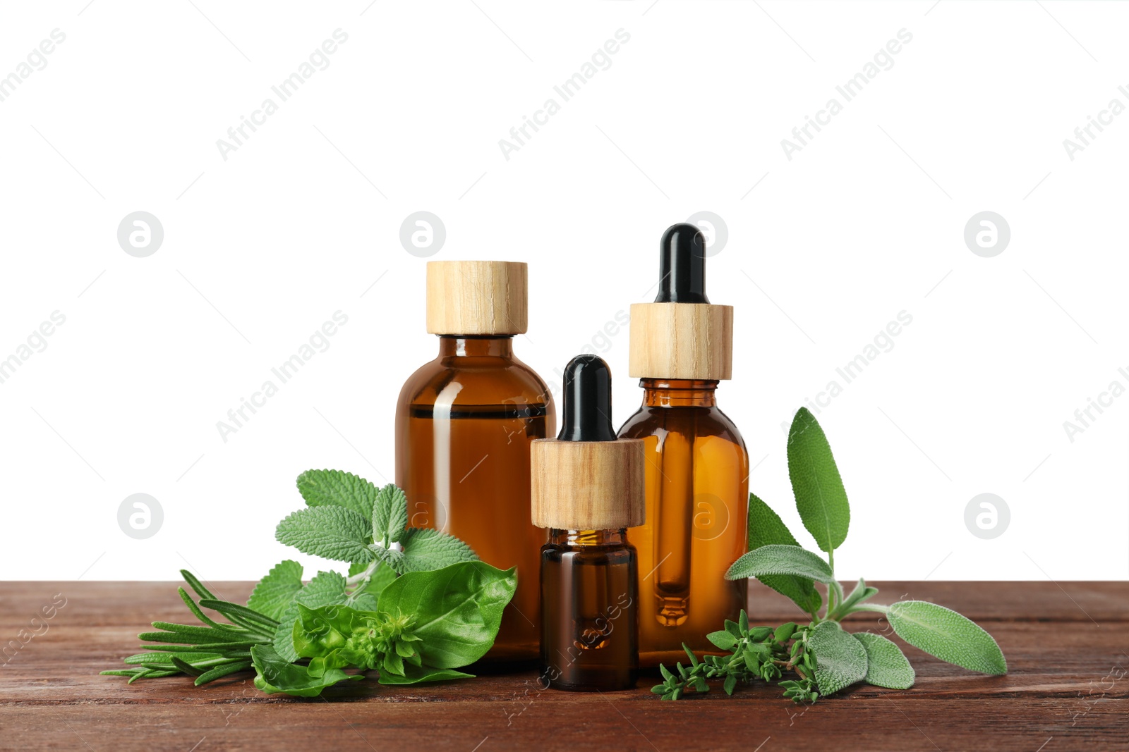 Photo of Bottles of essential oil and fresh herbs on wooden table against white background