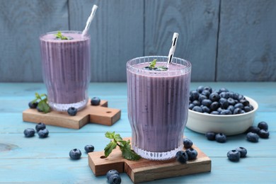 Photo of Tasty blueberry smoothie with mint and fresh berries on light blue wooden table
