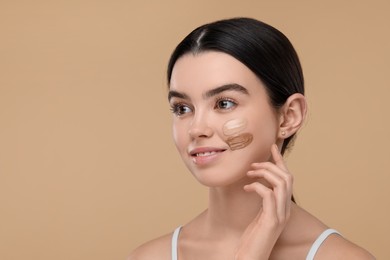 Photo of Teenage girl with swatches of foundation on face against beige background. Space for text