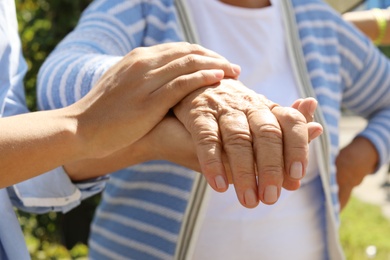 Photo of Helping hands on blurred background, closeup. Elderly care concept