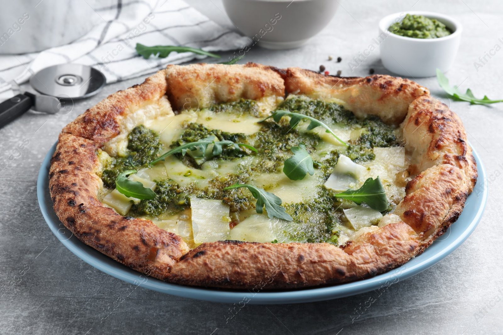 Photo of Delicious pizza with pesto, cheese and arugula on grey table, closeup