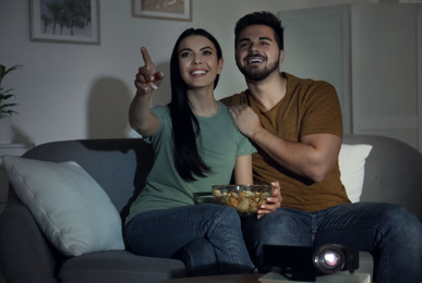 Young couple watching movie using video projector at home