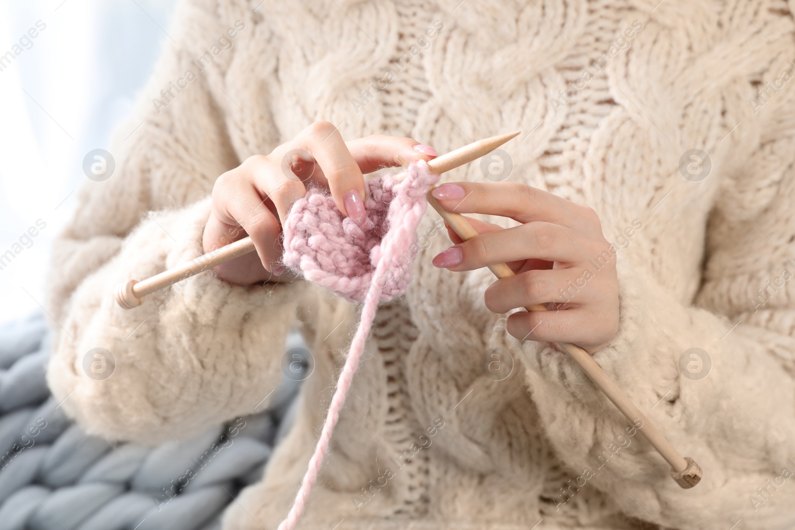 Photo of Beautiful teenage girl in warm cozy sweater knitting, closeup