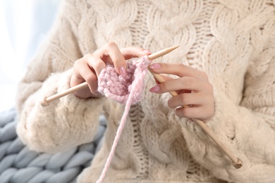 Photo of Beautiful teenage girl in warm cozy sweater knitting, closeup