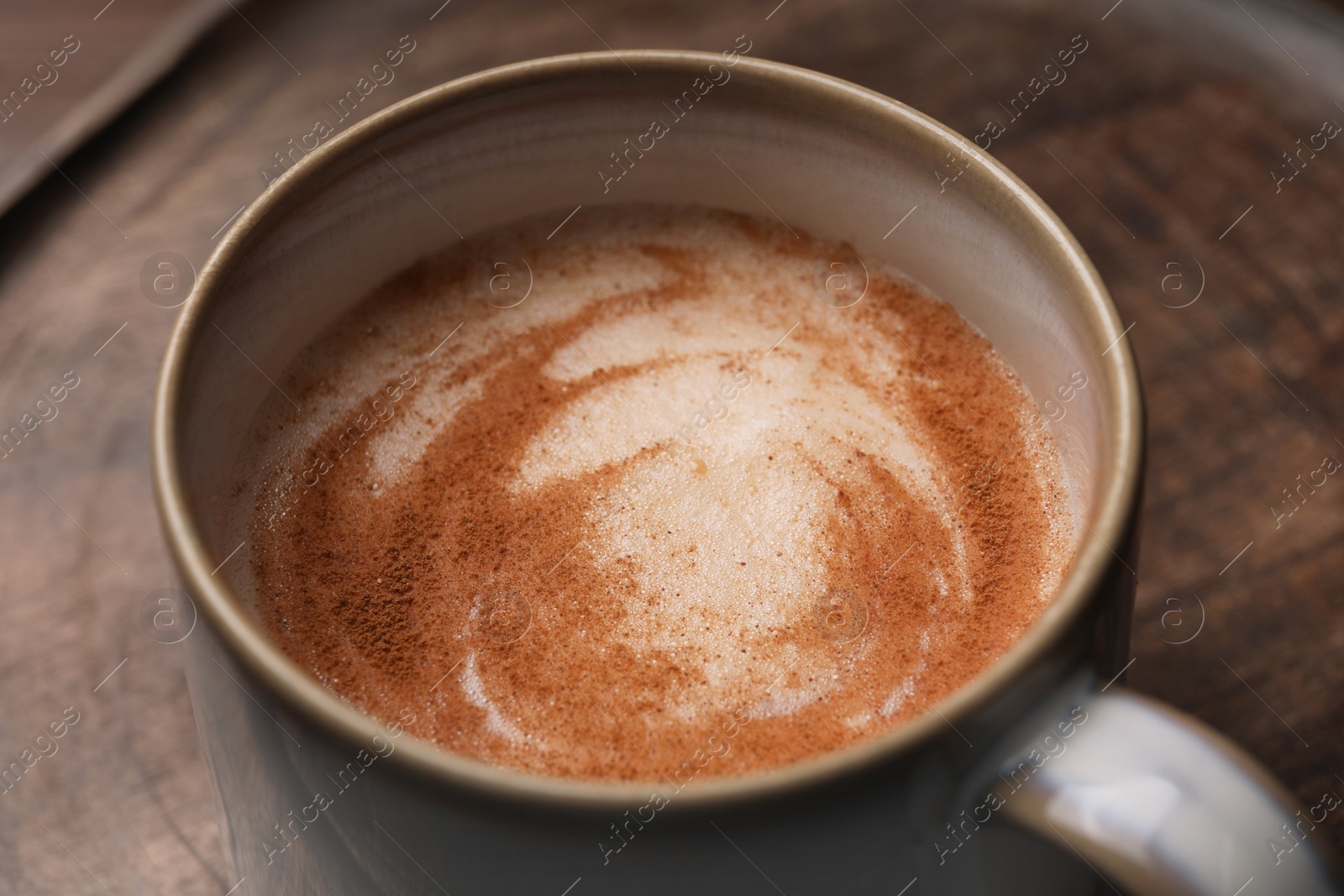 Photo of Cup of delicious eggnog on wooden tray, closeup