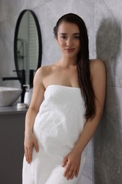 Beautiful young woman after shower in bathroom