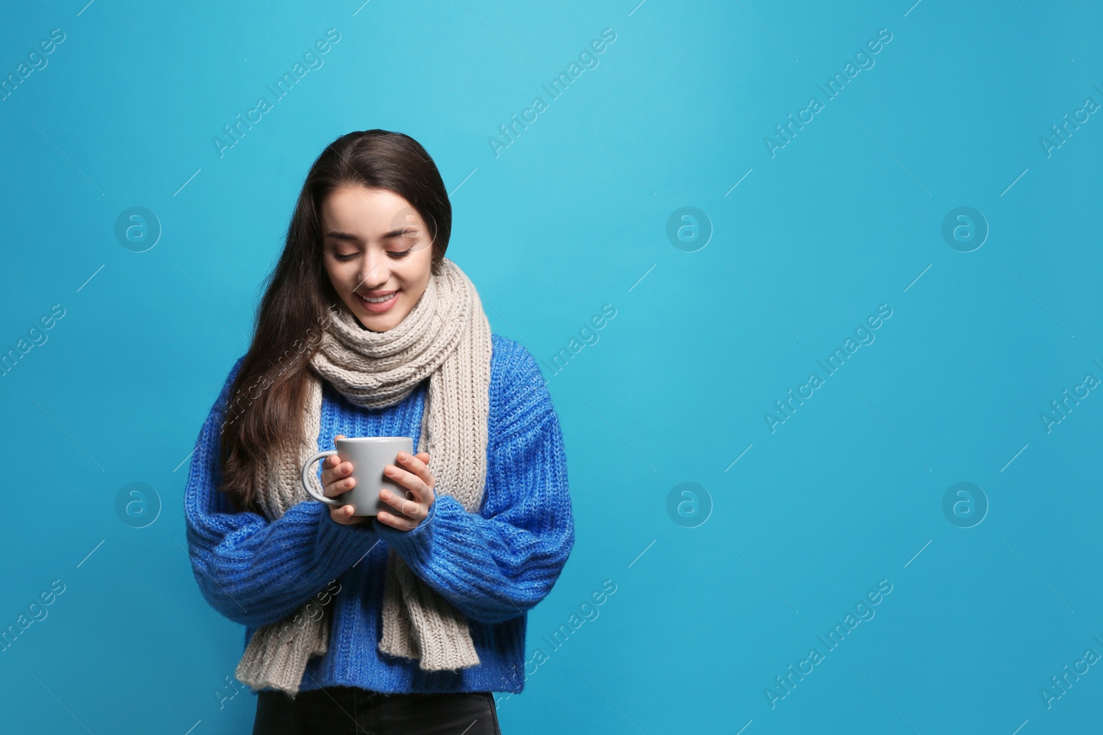 Photo of Young woman in sweater with cup of hot coffee on color background, space for text. Winter season