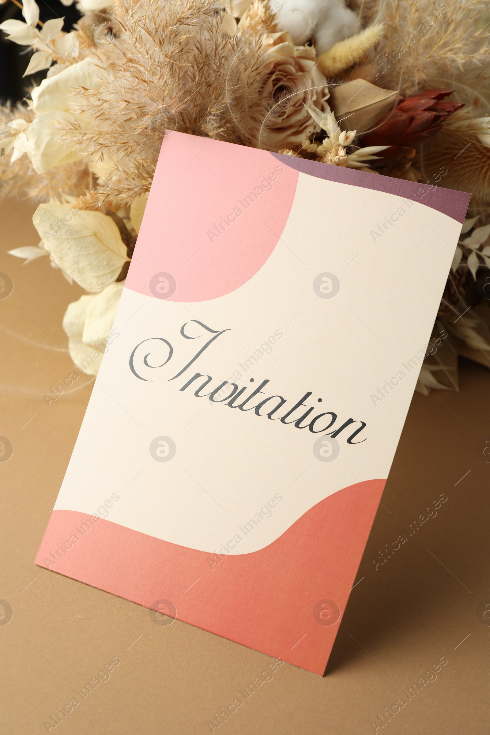 Photo of Beautiful card with word Invitation and dry flowers on beige background