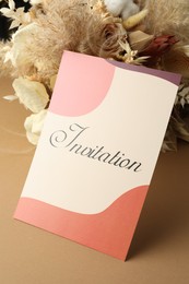 Beautiful card with word Invitation and dry flowers on beige background