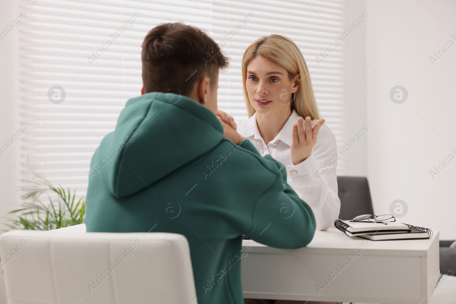 Photo of Psychologist working with teenage boy at table in office