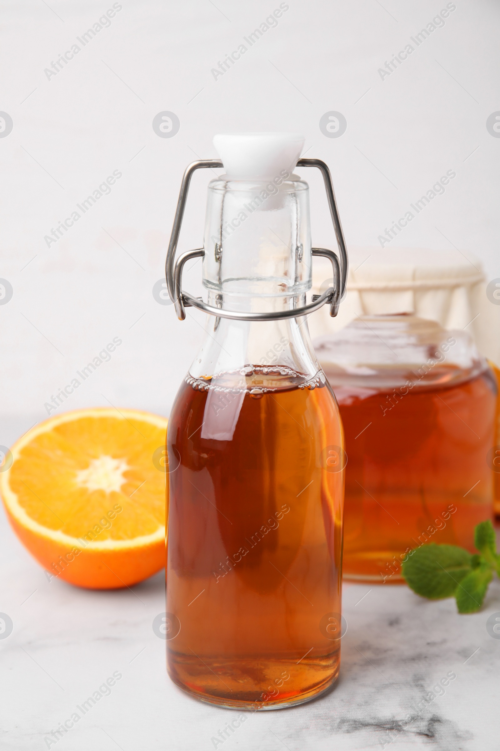 Photo of Tasty kombucha, orange and mint on white marble table