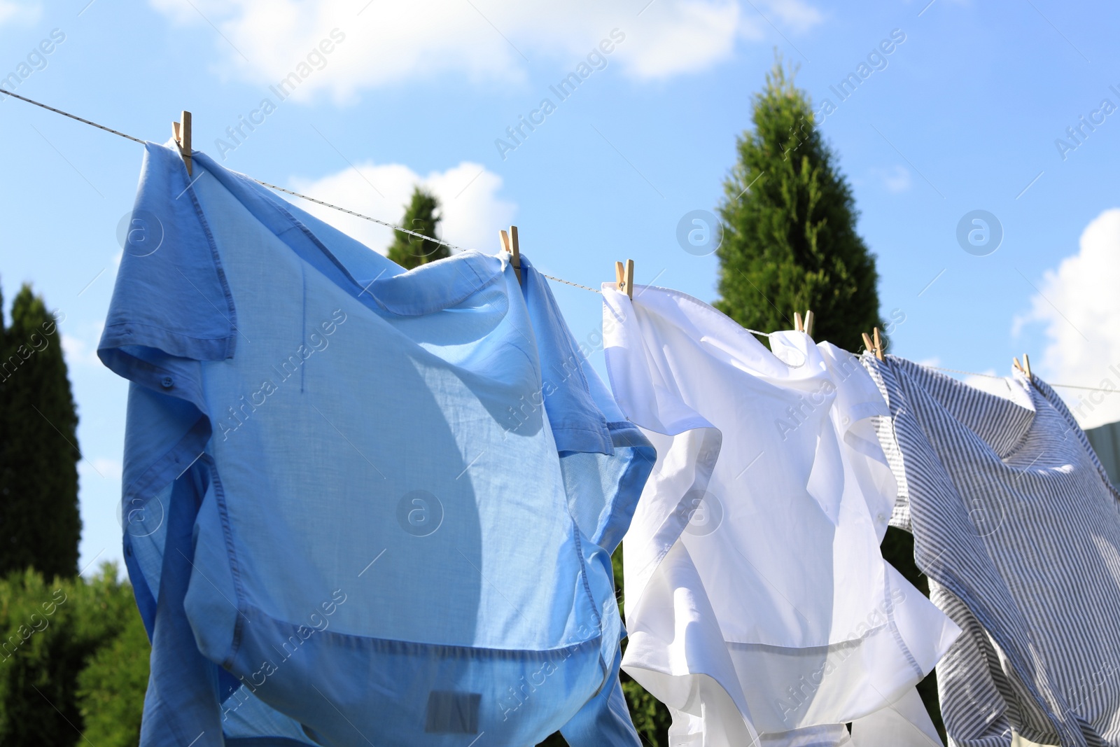 Photo of Clean clothes hanging on washing line in garden, closeup. Drying laundry