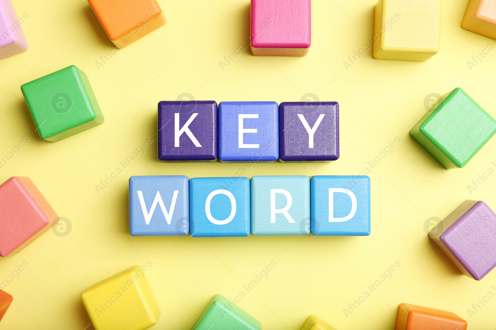 Photo of Colorful cubes with word KEYWORD on yellow background, flat lay