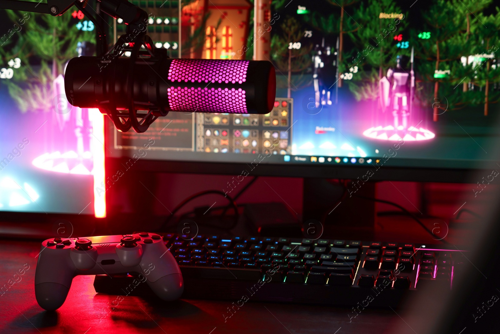 Photo of Playing video games. Modern computer, microphone and wireless controller on table indoors