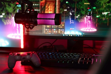 Playing video games. Modern computer, microphone and wireless controller on table indoors