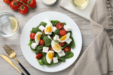 Photo of Delicious salad with boiled eggs, feta cheese and tomatoes served on wooden table, flat lay