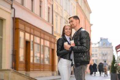 Photo of Lovely young couple with cups of coffee together on city street. Romantic date