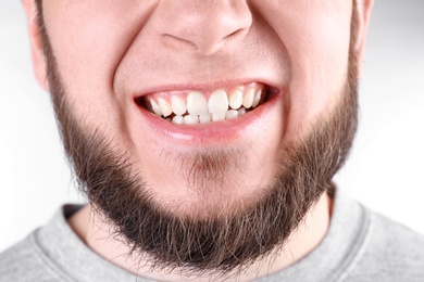 Young man with healthy teeth smiling on white background, closeup