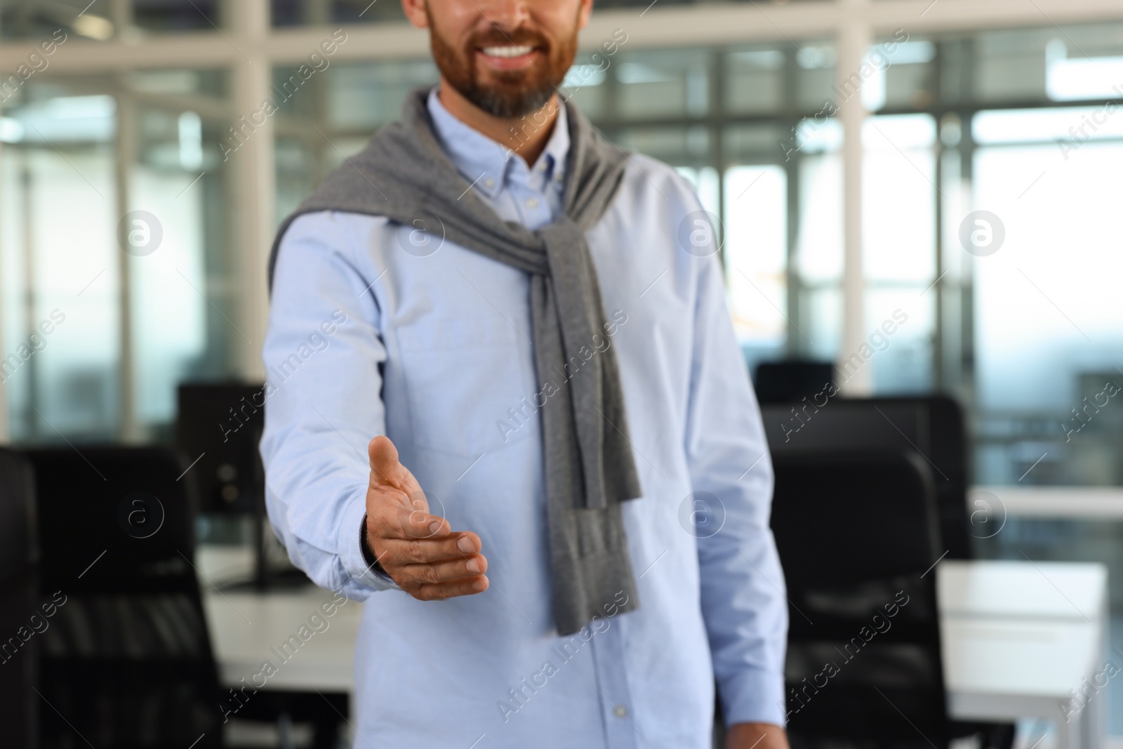 Photo of Man welcoming and offering handshake in office, closeup