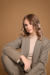 Portrait of young woman with beautiful makeup on light brown background