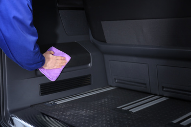 Photo of Worker wiping automobile trunk with rag at car wash, closeup