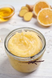 Body scrub in glass jar on white wooden table, closeup