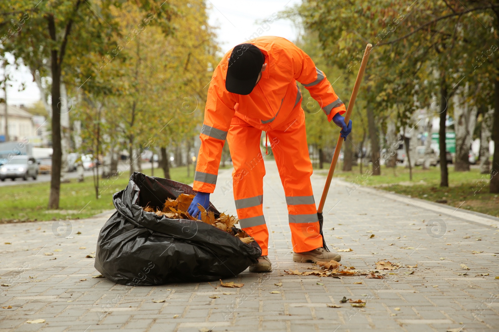 Photo of Worker cleaning street from fallen leaves on autumn day