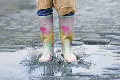 Photo of Woman in rubber boots walking outdoors on rainy day, closeup