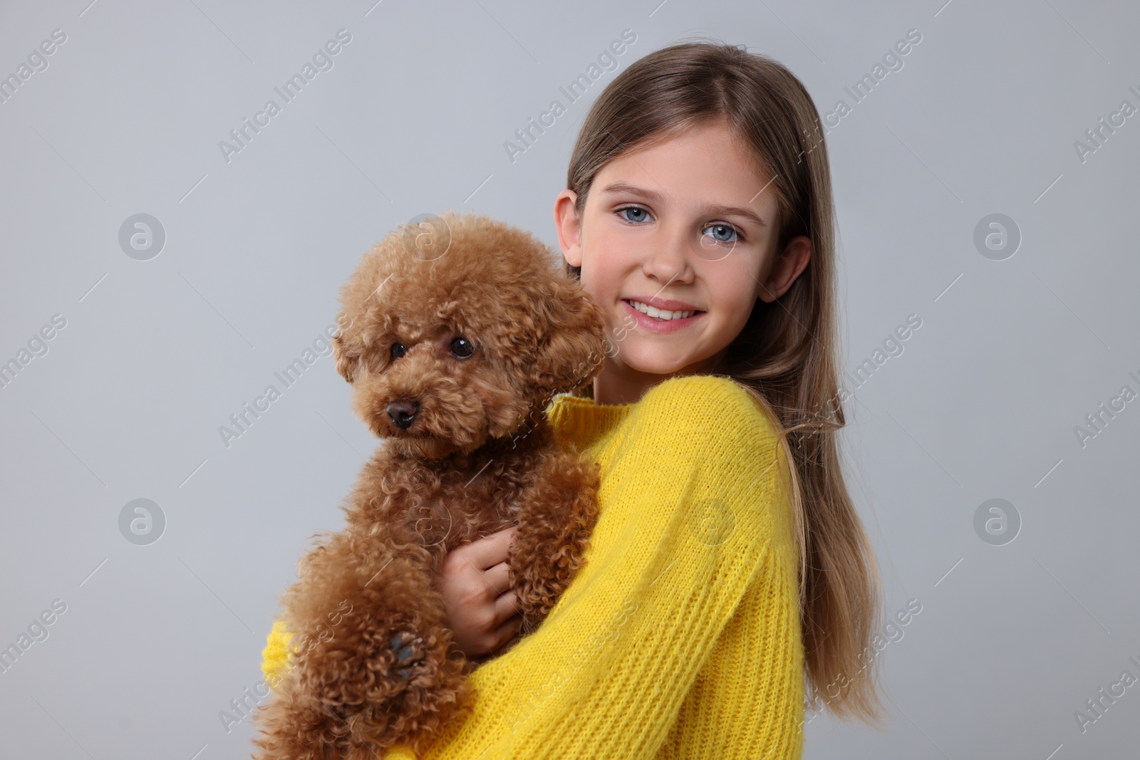 Photo of Little child with cute puppy on light grey background. Lovely pet